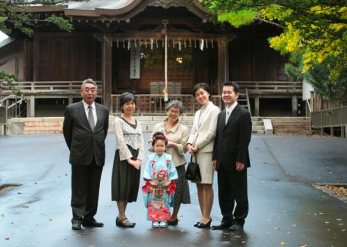 七五三記念の女の子を囲んで写る親族。神社本殿前で撮影しています。