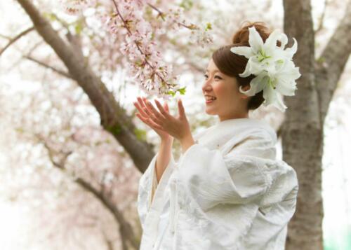 桜の花を手のひらでつつむように立つ花嫁。結婚写真。和装